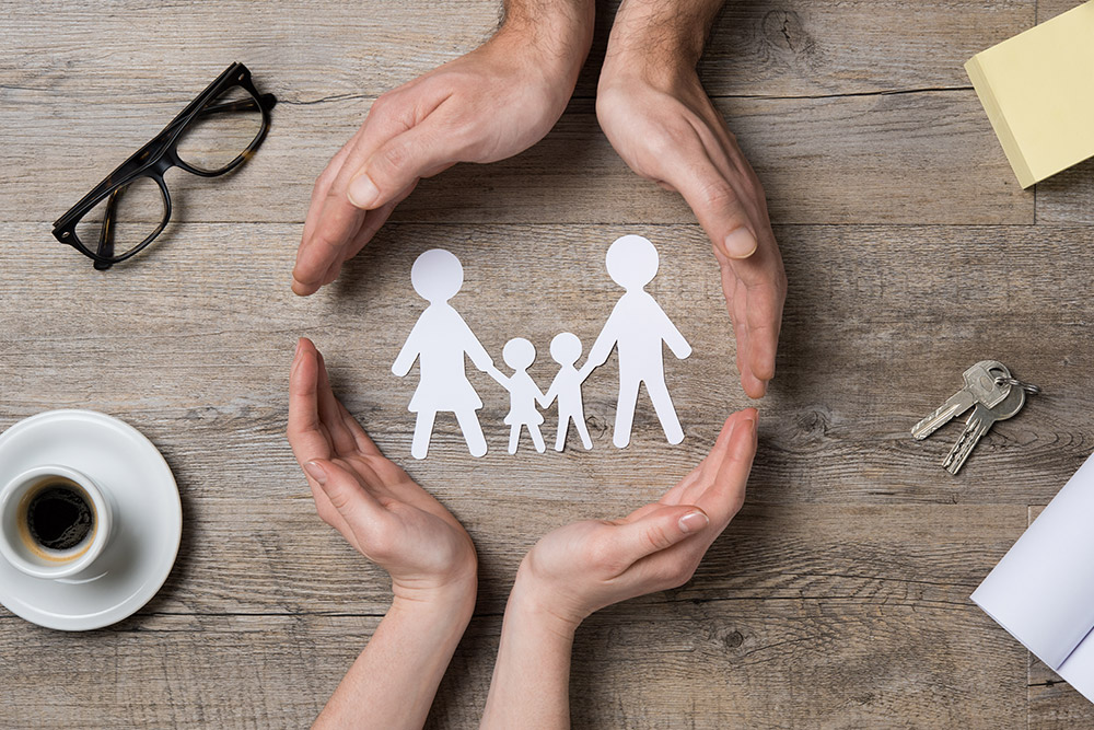 Close up of female and male hands protecting a paper chain family.