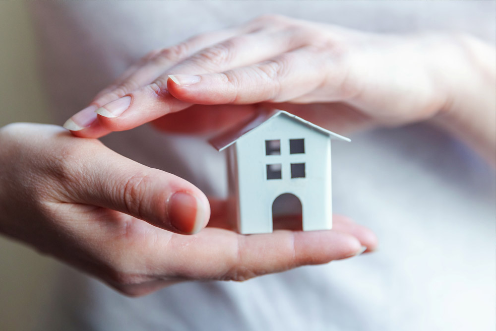 Female woman hands holding small miniature white toy house