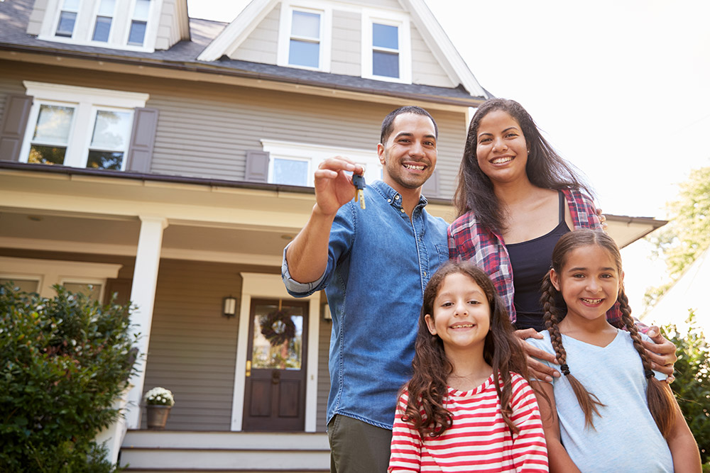 Portrait Of Hispanic Family Holding Keys To New Home On Moving In Day